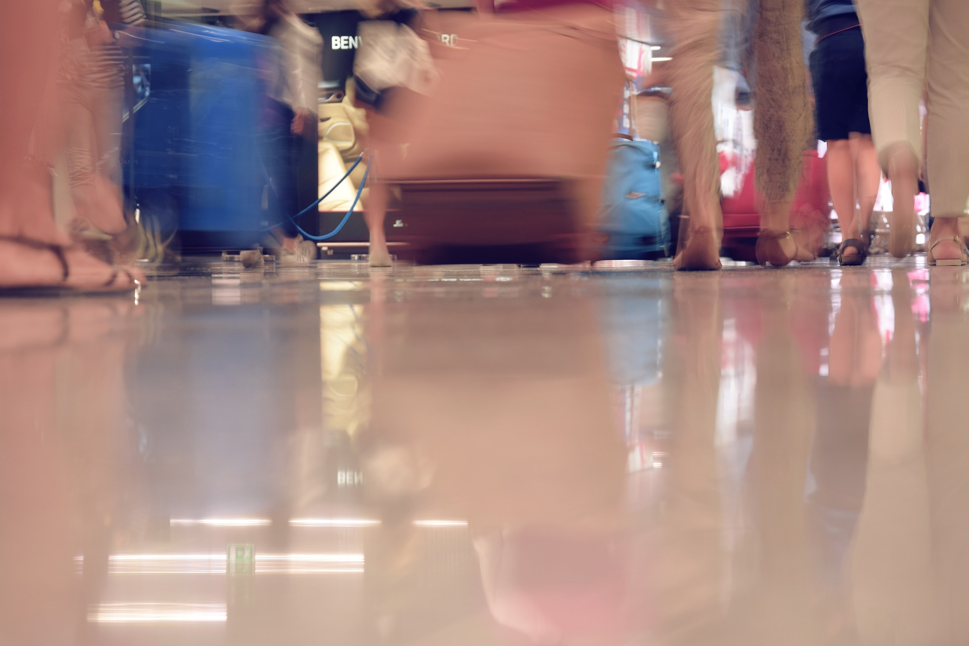 people and suitcases reflected in glossy airport floor Image by ilaria piras from Pixabay
